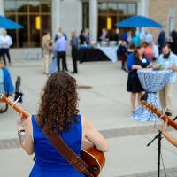 An overview shot of the band playing with guests mingling outside.